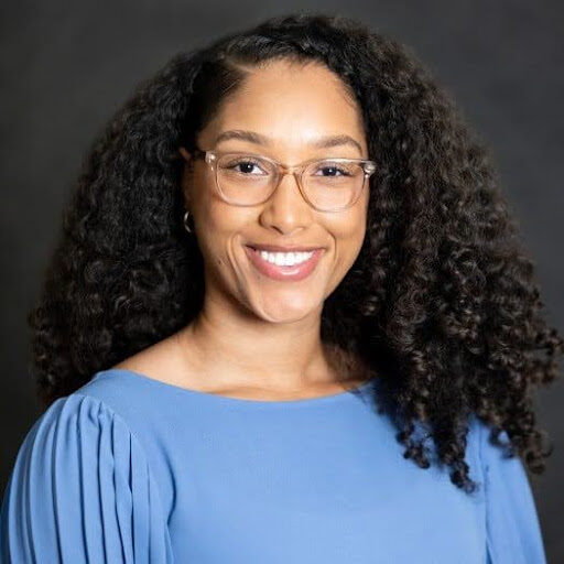 Headshot of light-skinned Black woman wearing glasses and a light blue blouse